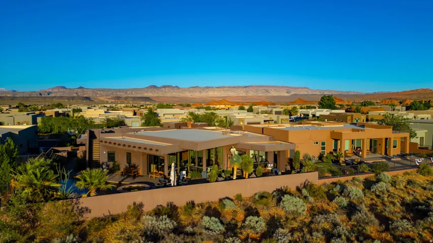 Contemporary desert architecture featuring a flat roofline, stucco exterior, and extensive glass doors opening to outdoor patio spaces
