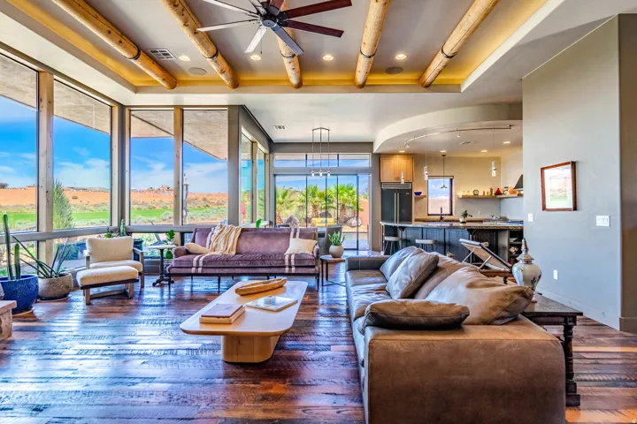 Spacious living area featuring expansive windows, wood-finish flooring, exposed ceiling beams, a ceiling fan, and recessed lighting