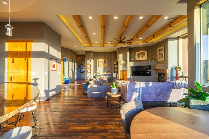 Spacious open-concept living area featuring wood-finish flooring, exposed ceiling beams, recessed lighting, and a ceiling fan