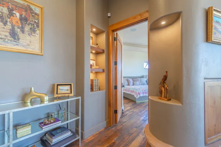 Hallway featuring wood-finish flooring, built-in display niches with integrated lighting, and solid wood trim