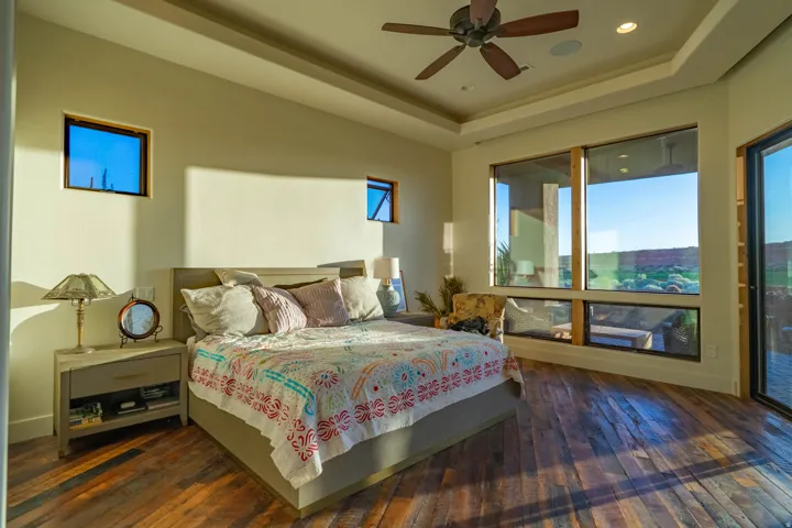 Expansive bedroom featuring large picture windows, wood-finish flooring, a ceiling fan, and recessed lighting