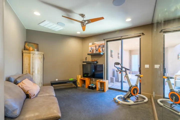 Flexible-use room featuring a ceiling fan with integrated lighting, recessed lighting, and dark-toned flooring