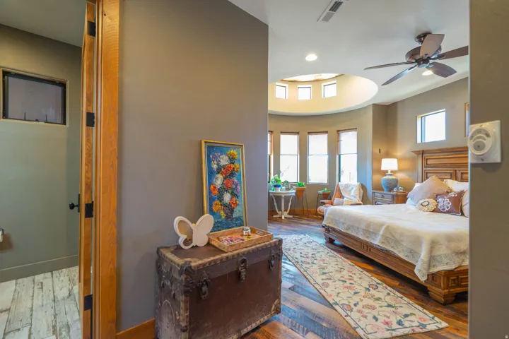 Bedroom featuring wood-finish flooring, a tray ceiling with recessed lighting, a ceiling fan, and multiple windows