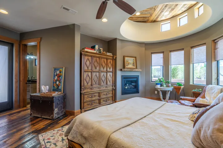 Bedroom featuring wood-finish flooring, a built-in fireplace with a stone mantel, and a domed ceiling with perimeter windows