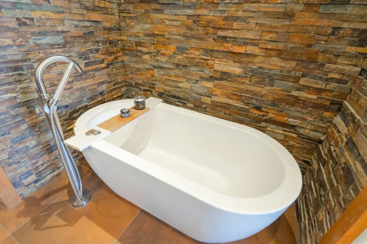 Freestanding soaking tub with a floor-mounted brushed metal faucet
