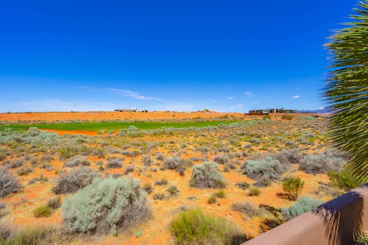 Expansive desert landscape featuring natural vegetation and distant structures under a clear blue sky
