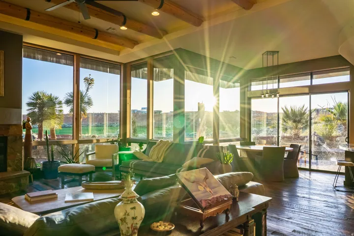 Expansive living space featuring a stone fireplace, wood-finish flooring, and exposed ceiling beams