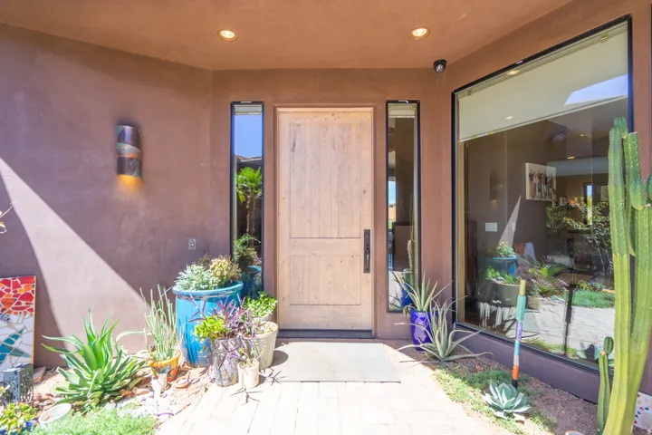Stucco exterior featuring a wood-panel entry door with a dark handle, flanked by narrow vertical windows
