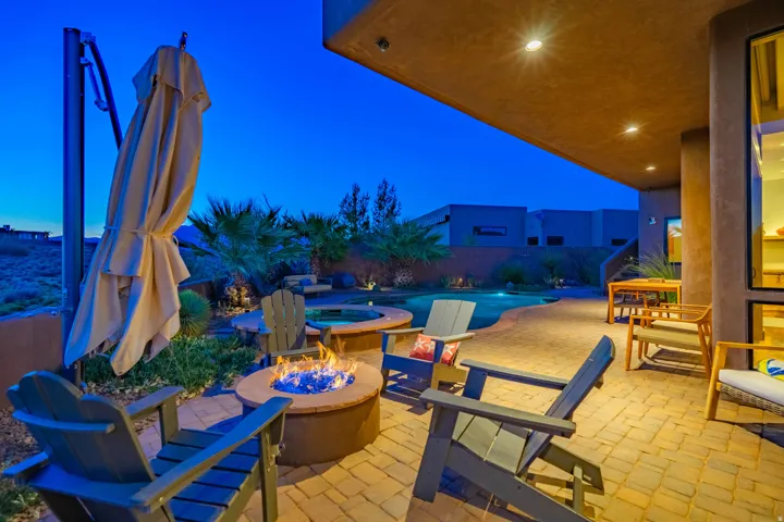 Outdoor living space featuring a paver patio, integrated fire pit, and an in-ground pool with a spa
