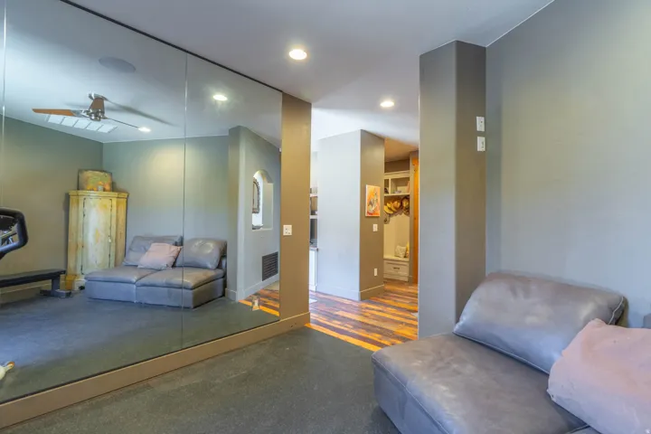 Full wall mirrored accent, recessed lighting, and durable flooring in a versatile room