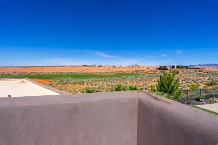 Expansive desert landscape with natural flora and distant green spaces
