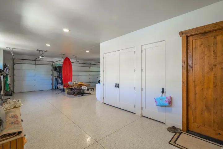 Spacious garage featuring a durable speckled epoxy floor, recessed lighting, and multiple garage doors