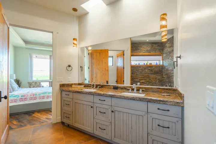 Dual vanity with a stone-finish countertop, undermount sinks, and a full-width mirror