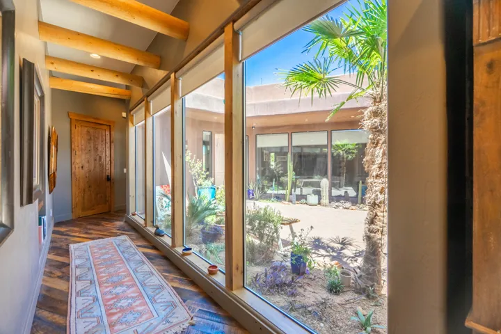 Interior hallway featuring exposed wood beams, wood-finish flooring, and a solid wood door