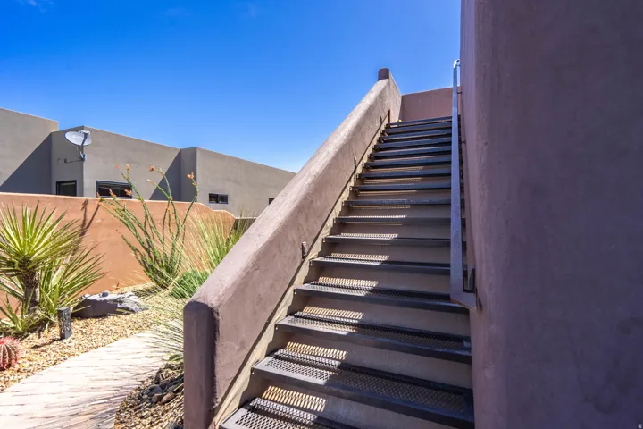 Exterior staircase with perforated metal treads and a stucco-finished railing