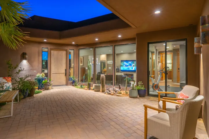 Expansive brick paver patio featuring a natural wood entry door and multiple full-height glass panels