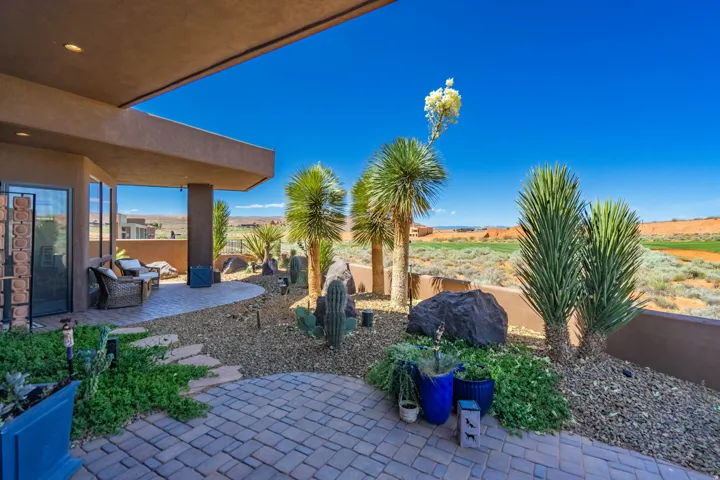 Expansive outdoor living area featuring a covered patio, paver stone walkway, and desert landscaping