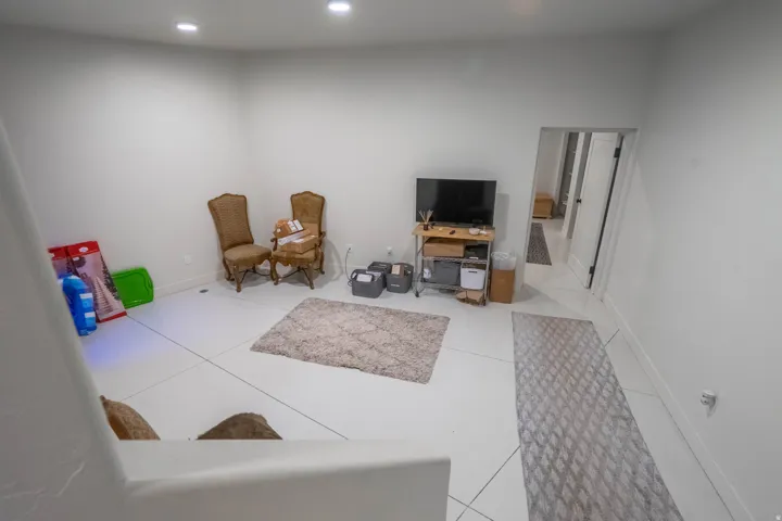 Spacious room featuring light-colored tile flooring, recessed ceiling lighting, and crisp white walls