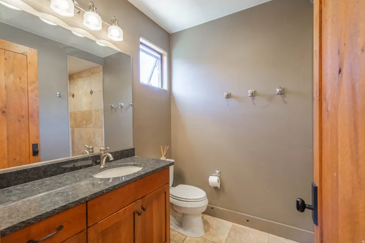 Bathroom featuring a vanity with a dark countertop, an undermount sink, and wood cabinetry