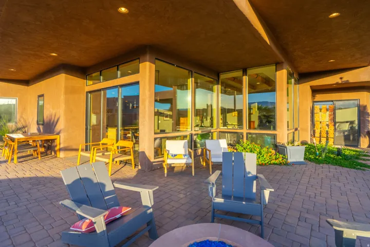Spacious covered patio featuring paver flooring, a built-in fire pit, and extensive window walls