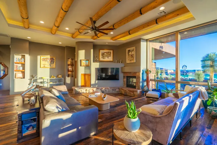 Spacious living area featuring wood-finish flooring, a stone-clad fireplace with a mounted television, and built-in shelving