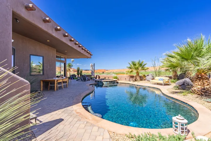 Curved swimming pool with an integrated spa, surrounded by a paved patio