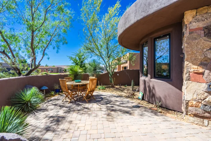 Paved patio area featuring a low stucco wall and mature desert landscaping
