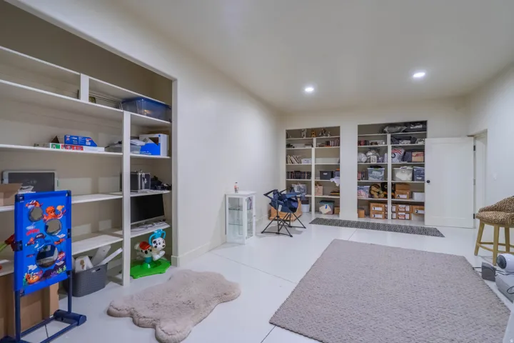 Spacious room featuring multiple built-in shelving units, recessed lighting, and light-colored flooring