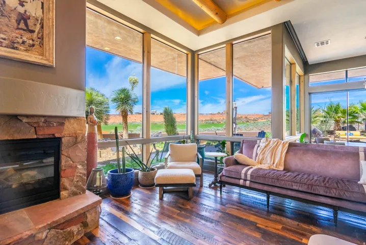 Expansive living space featuring a stone-clad fireplace with a hearth, wood-finish flooring, and a beamed ceiling
