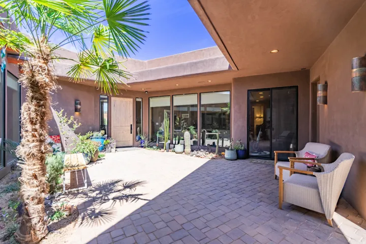 Private courtyard entry featuring a stone paver patio and mature palm tree