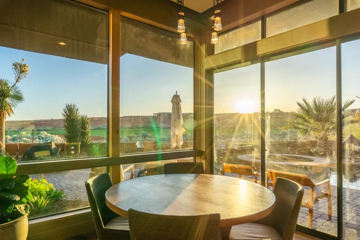 Spacious dining area featuring floor-to-ceiling windows, wood-finish framing, and a perimeter of retractable solar shades