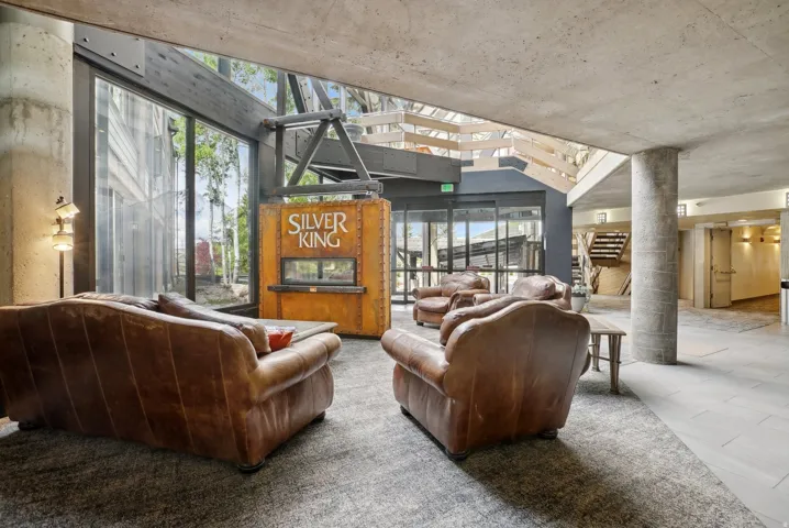 Spacious common area featuring an exposed concrete ceiling, large format window walls, and a distinctive "Silver King" kiosk