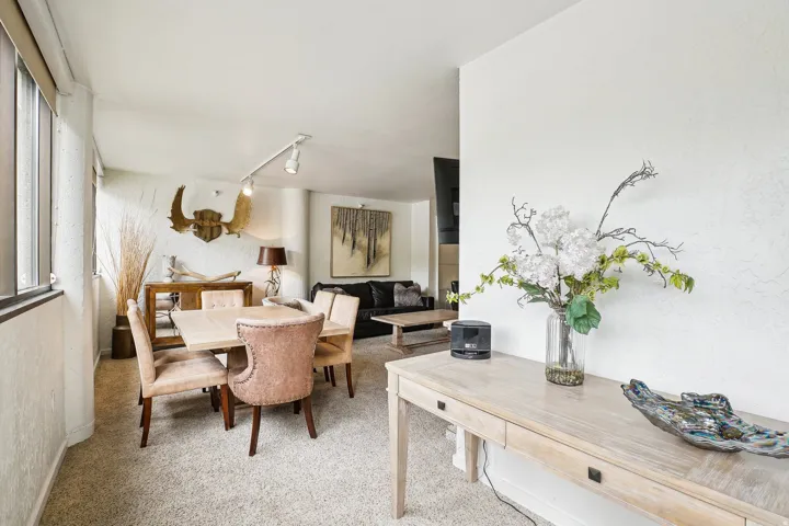 Open-concept living area featuring light-colored carpeting throughout
