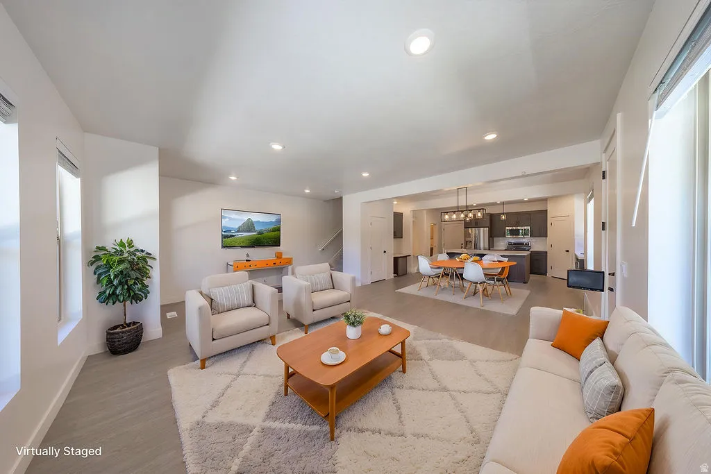 Virtually Staged.Open-concept living space featuring wood-finish flooring, recessed lighting, and ample natural light