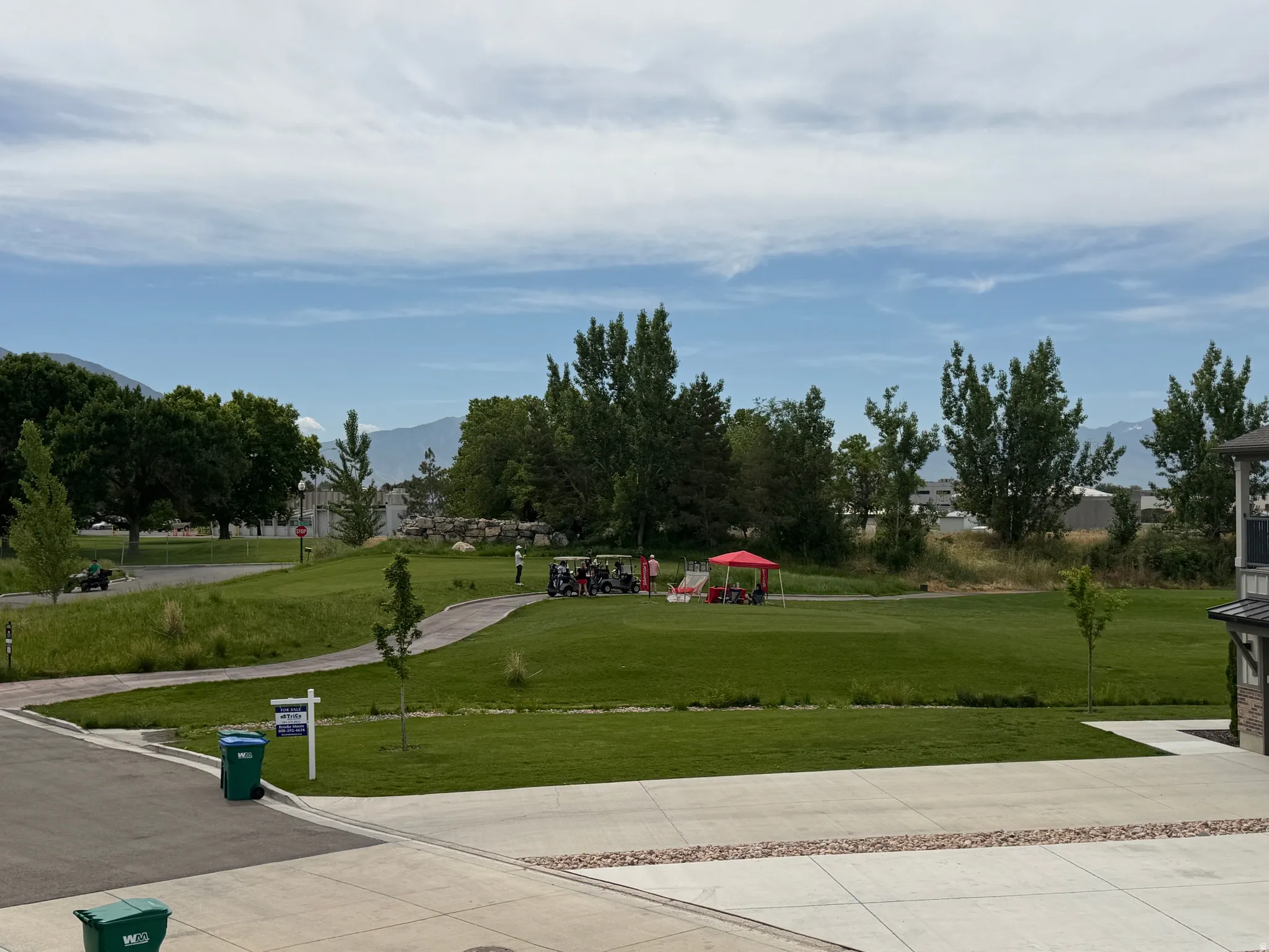 Expansive green space featuring a golf course, mature trees, and mountainous terrain in the distance