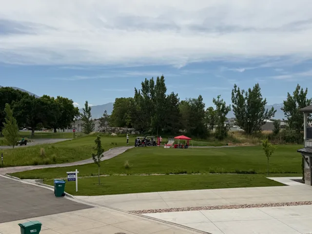 Expansive green space featuring a golf course, mature trees, and mountainous terrain in the distance