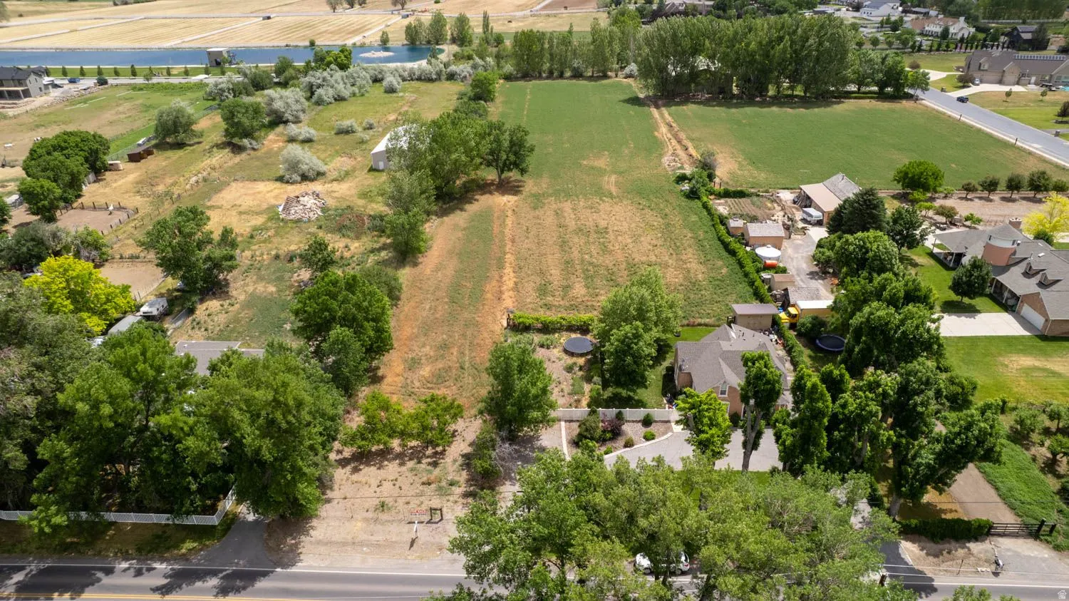 Expansive undeveloped land parcel featuring mature trees, a partially cleared area, and surrounding residential properties