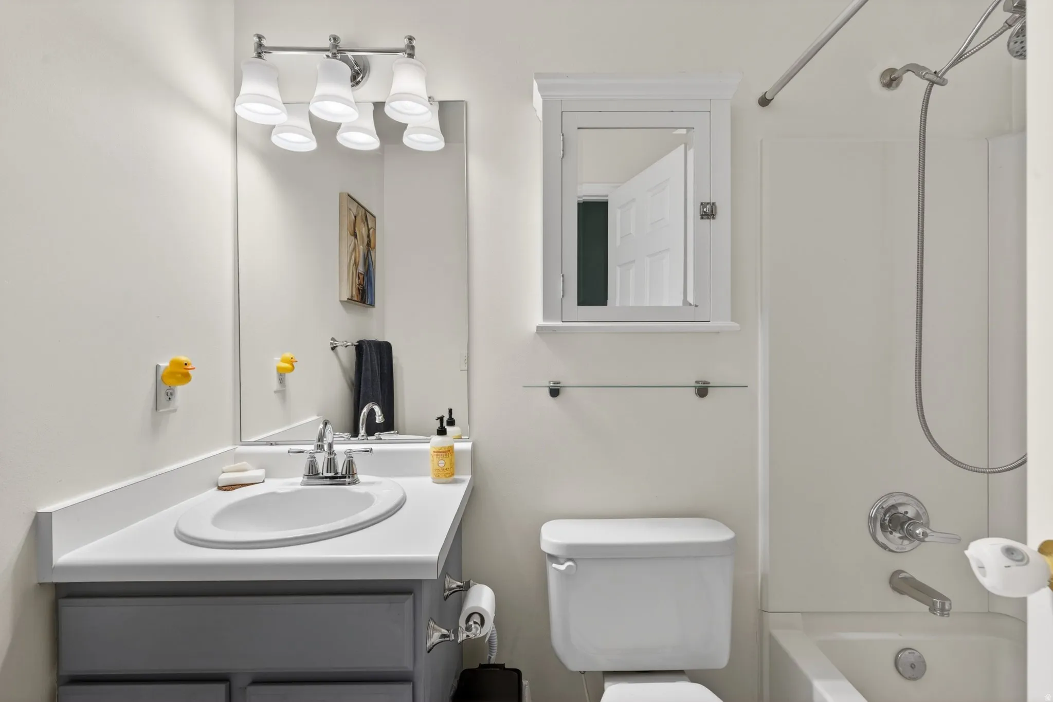 Bathroom featuring a vanity with an integrated sink, a medicine cabinet, a full mirror, and a shower-over-tub combination with a curved shower rod