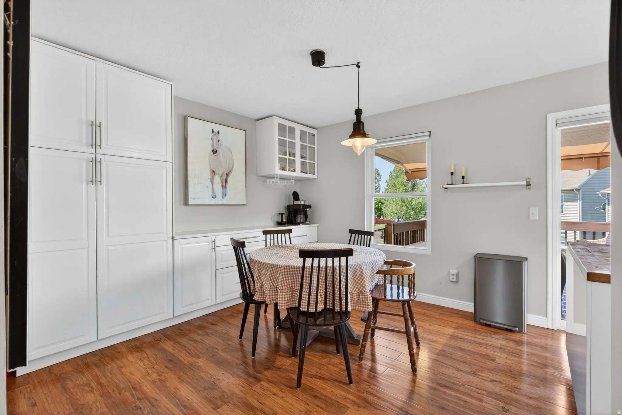 Kitchen featuring wood-finish flooring, white cabinetry, and a window with outdoor deck views
