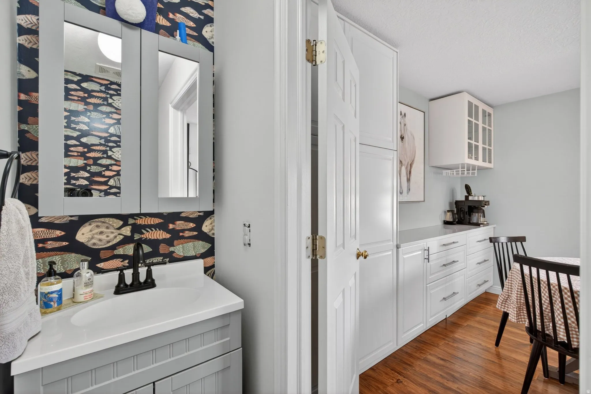 Vanity with a white countertop and a matte black faucet, set against patterned wallpaper