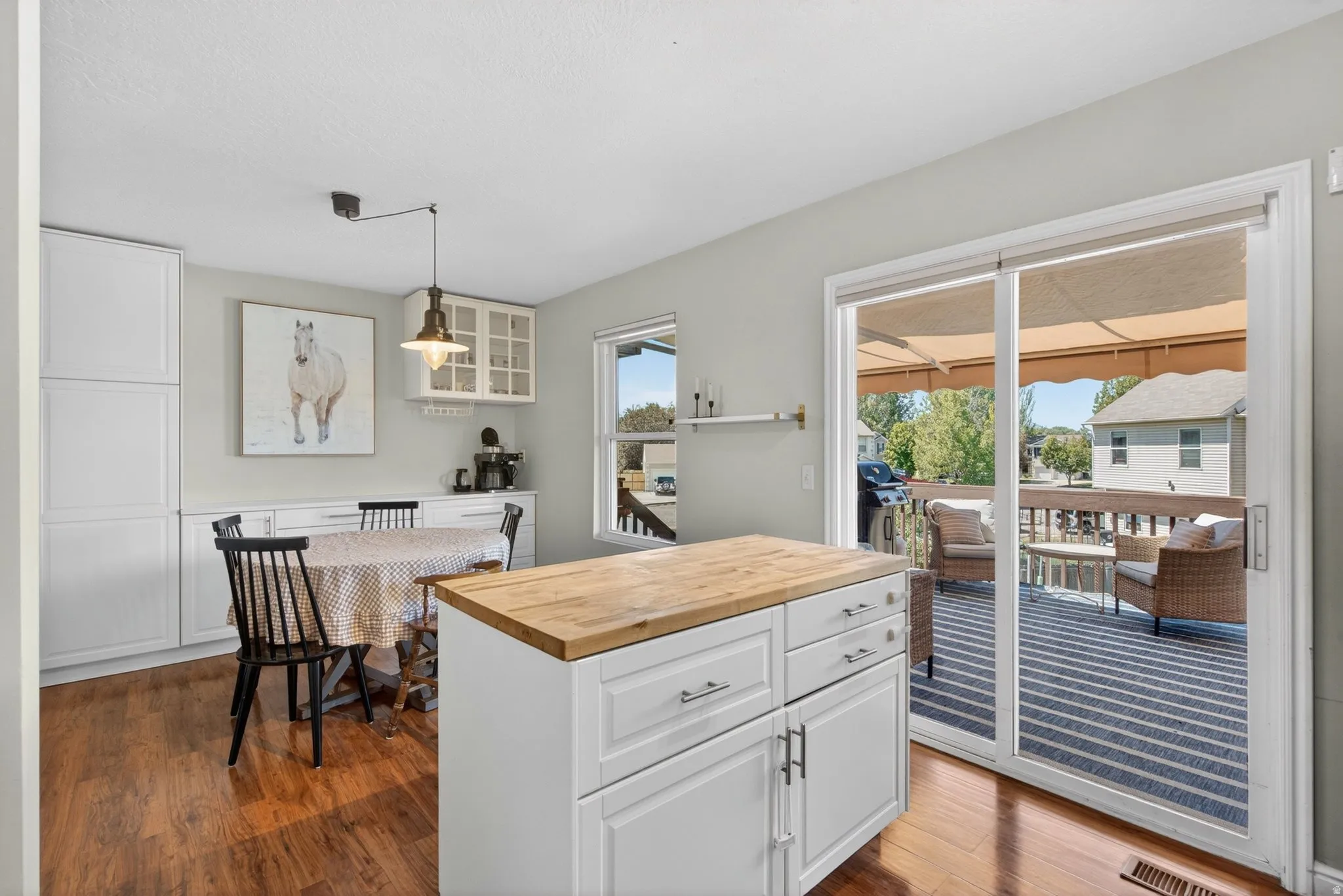 Kitchen area with wood-finish flooring, white cabinetry, and a kitchen island with a wood countertop