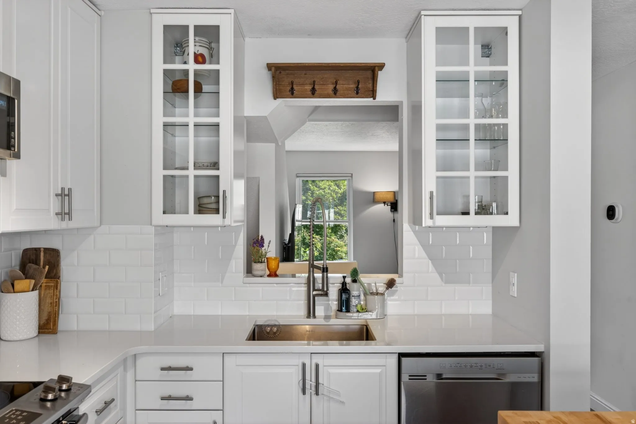 Contemporary kitchen featuring white cabinetry with brushed nickel hardware, subway tile backsplash, and light-toned countertops