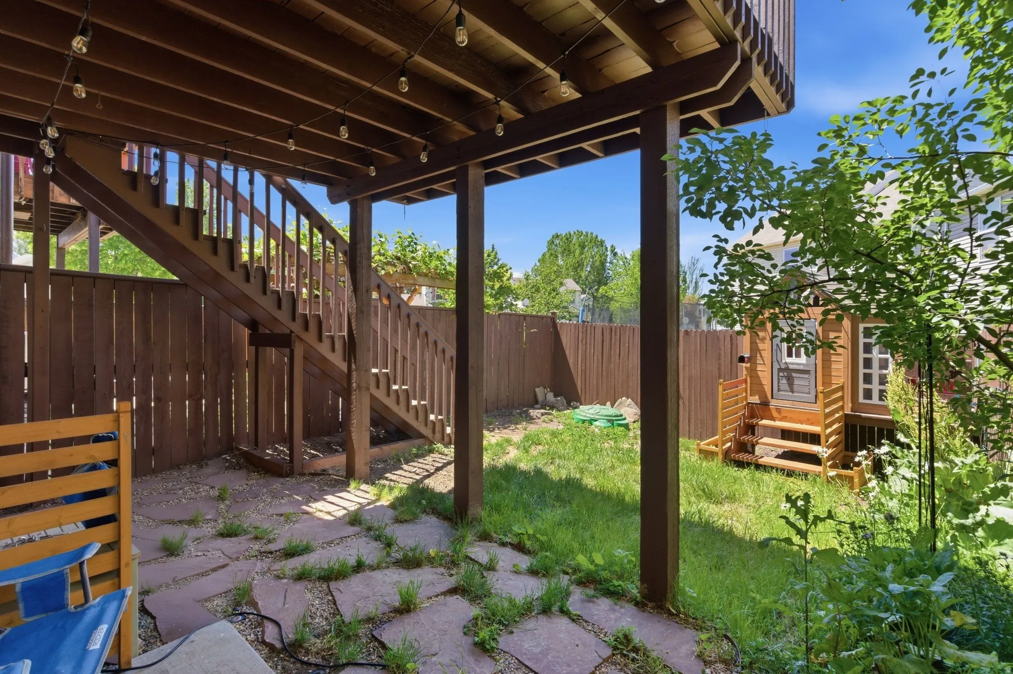 Under-deck patio area featuring string lighting and stone pavers