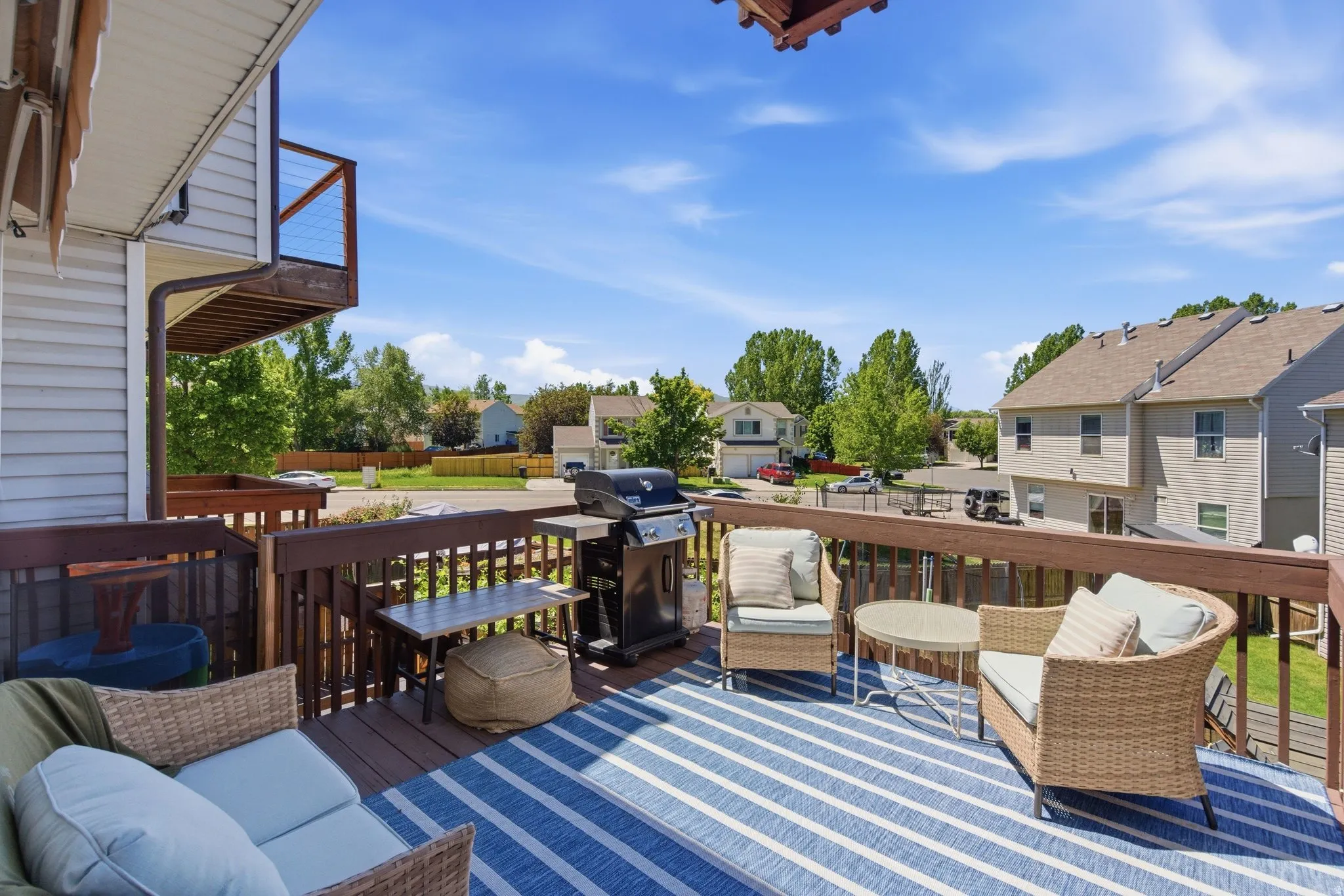 Spacious outdoor deck featuring wood decking, a full-height railing system, and a partial second-story balcony