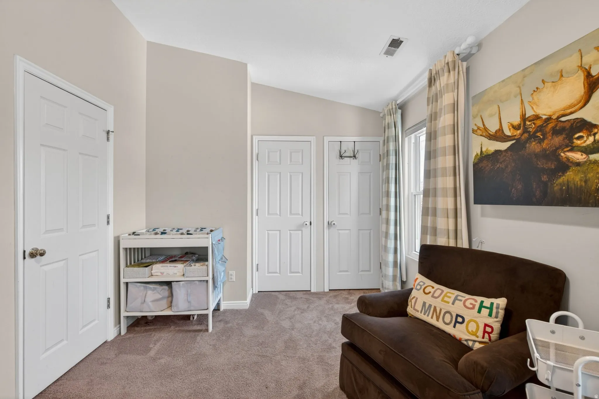 Carpeted room featuring neutral wall tones and a vaulted ceiling