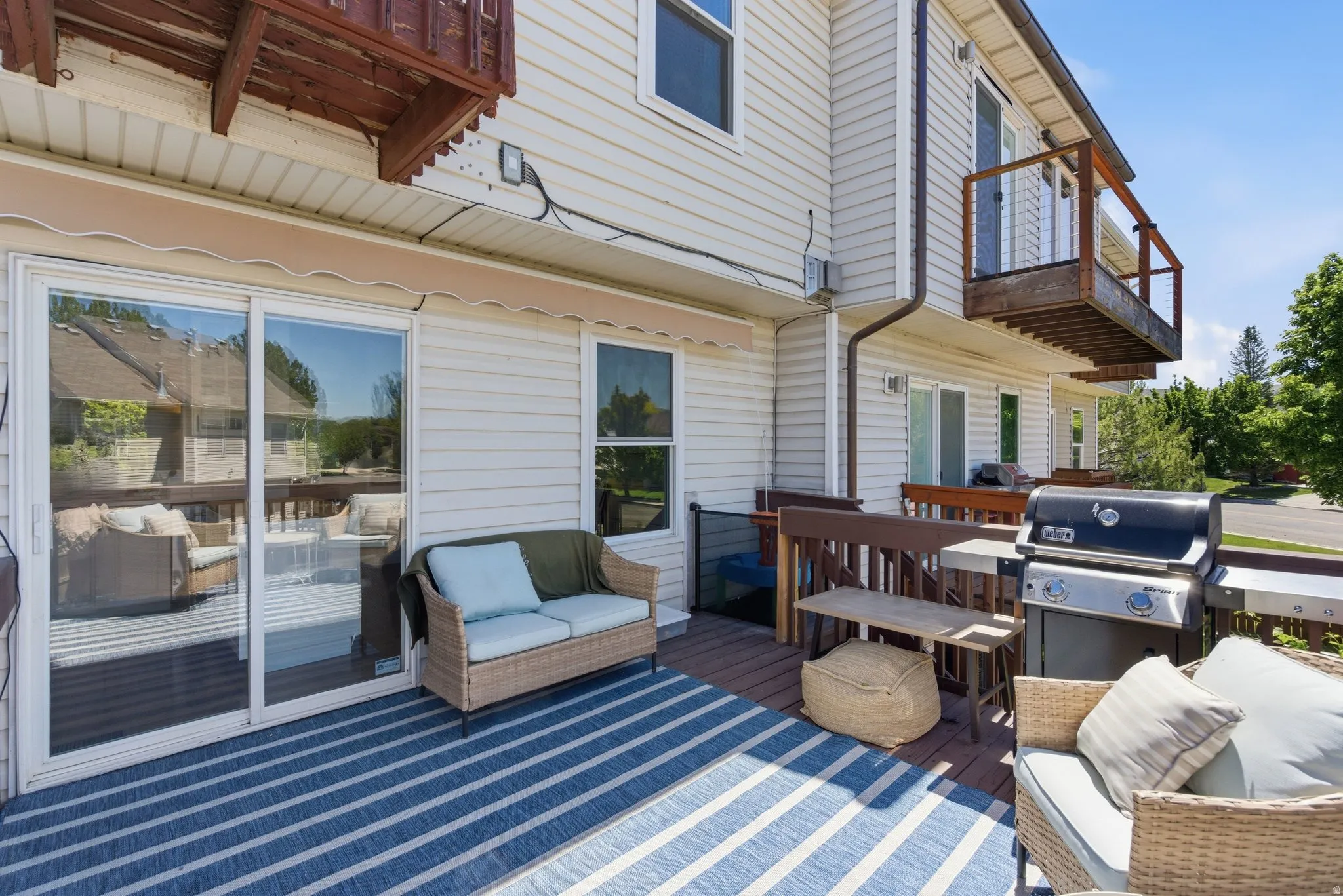 Expansive outdoor deck featuring wood-finish flooring, a full-lite sliding patio door, and an upper-level balcony
