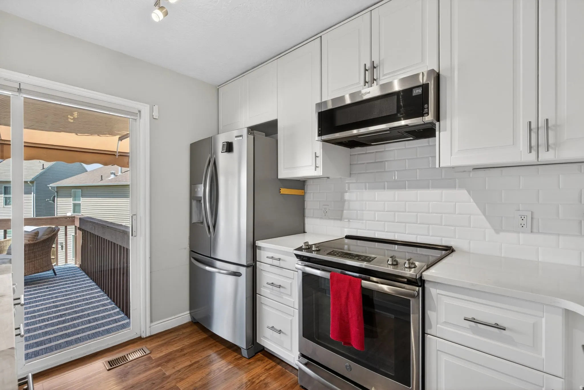 Contemporary kitchen featuring stainless steel appliances, white cabinetry with brushed nickel hardware, subway tile backsplash, and light-toned countertops