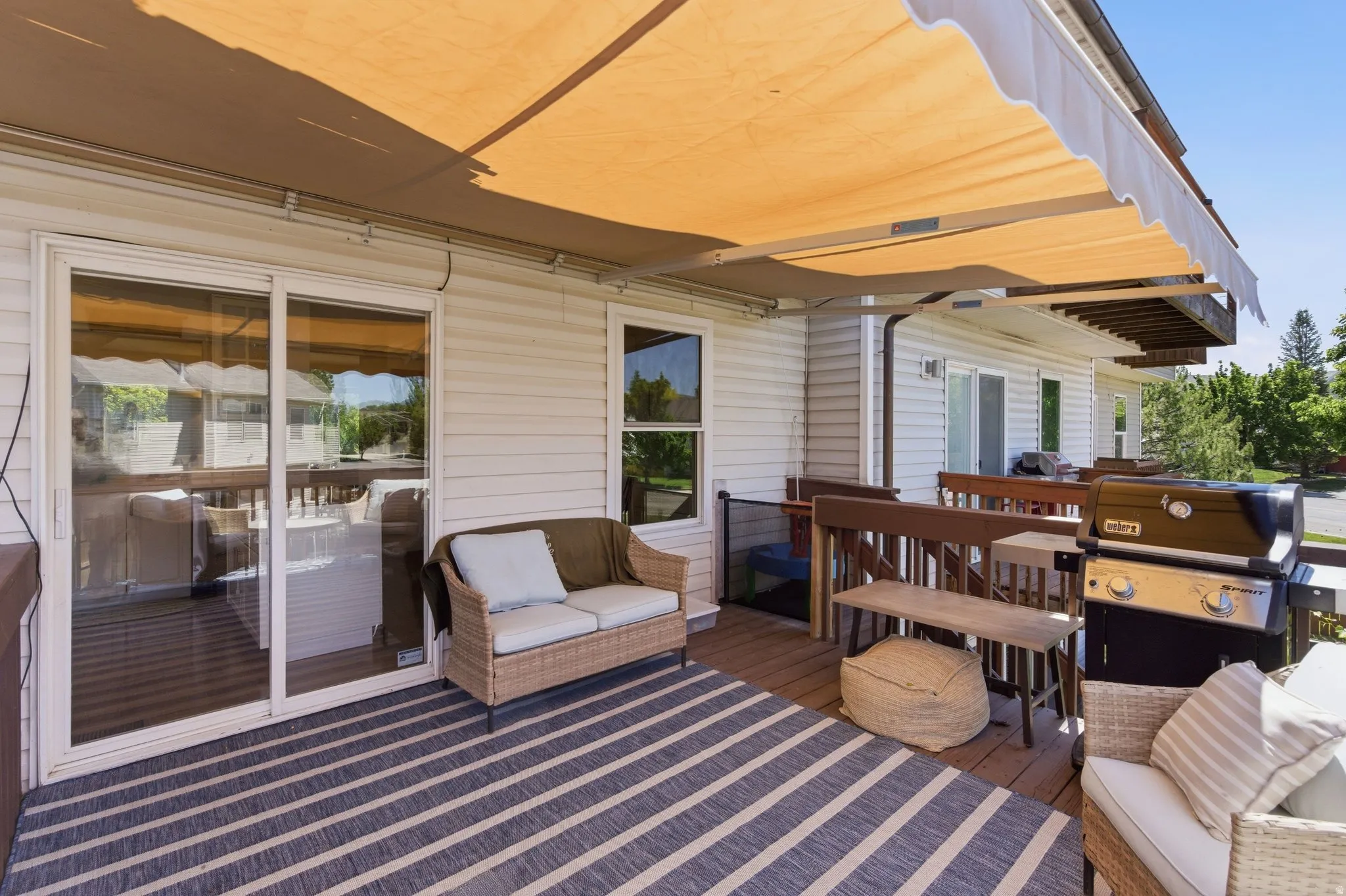 Expansive outdoor deck featuring wood-finish flooring and a retractable awning
