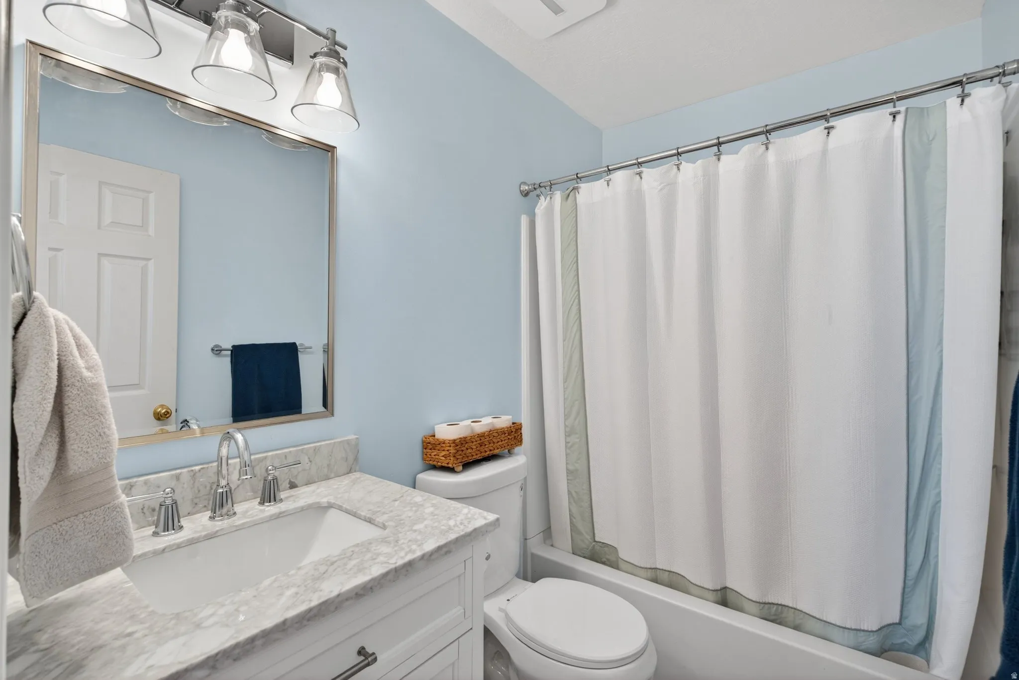 Bathroom featuring a single vanity with stone-finish countertop, undermount sink, and polished chrome faucet