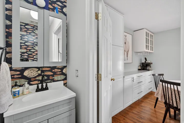 Vanity with a white countertop and a matte black faucet, set against patterned wallpaper